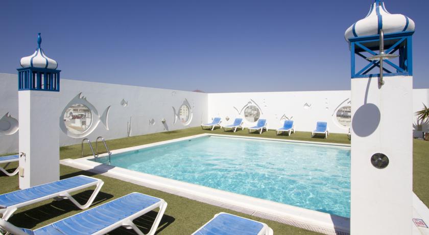 Zwembad met zonnebedjes aan beide kanten van hotel Lancelot op Lanzarote